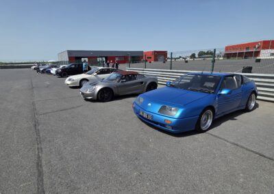 Alpine V6 bleue et voitures de sport dans la voie des stands du circuit de La Ferté-Gaucher